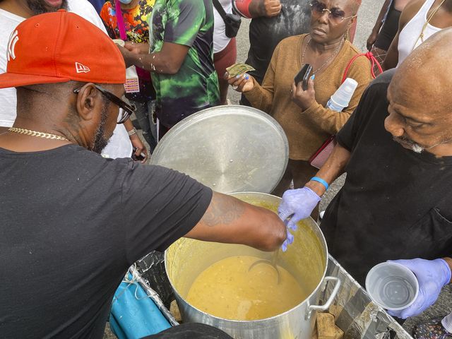 A man uses his ladle to dish up servings of corn soup as people line up in front of his stand on Monday, September 5, 2022.
